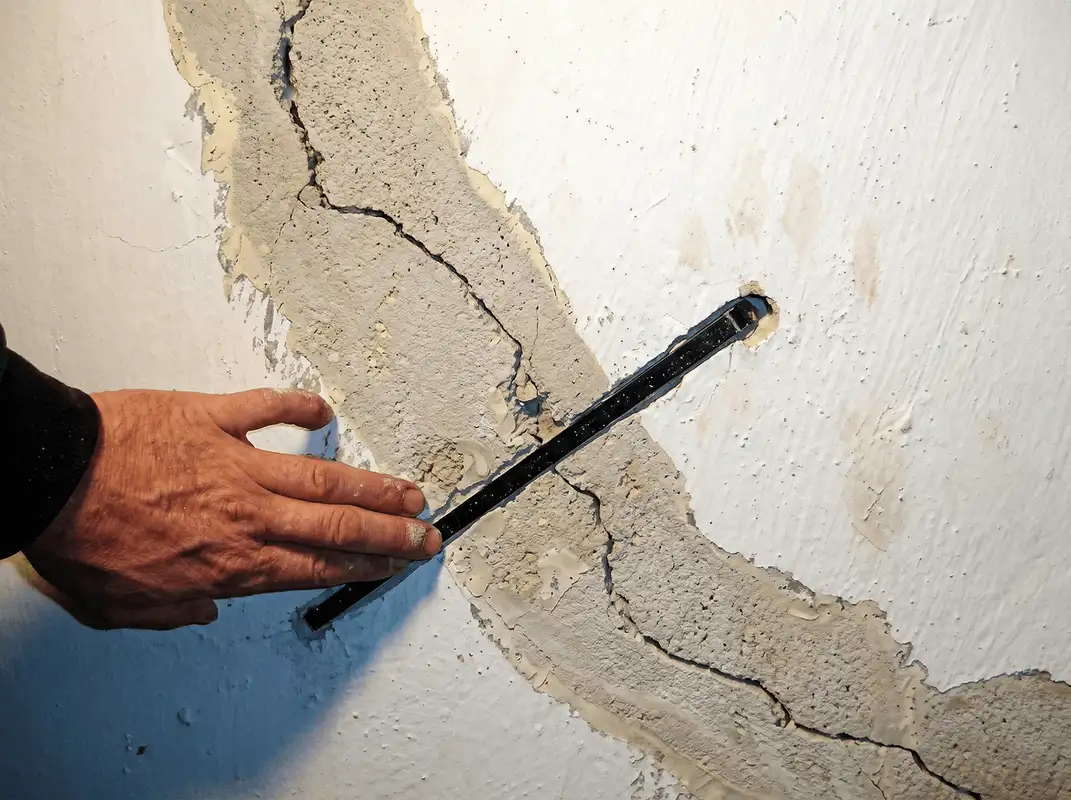 A wall with a large crack is being inspected by a professional in San Francisco, CA