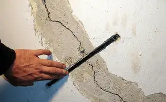 A wall with a large crack is being inspected by a professional in San Francisco, CA